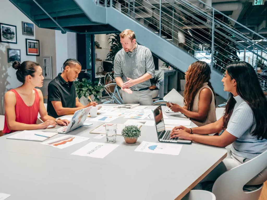 Ein diverses Team von Geschäftsleuten, die in einem modernen Büro zusammenarbeiten und sich unterhalten.